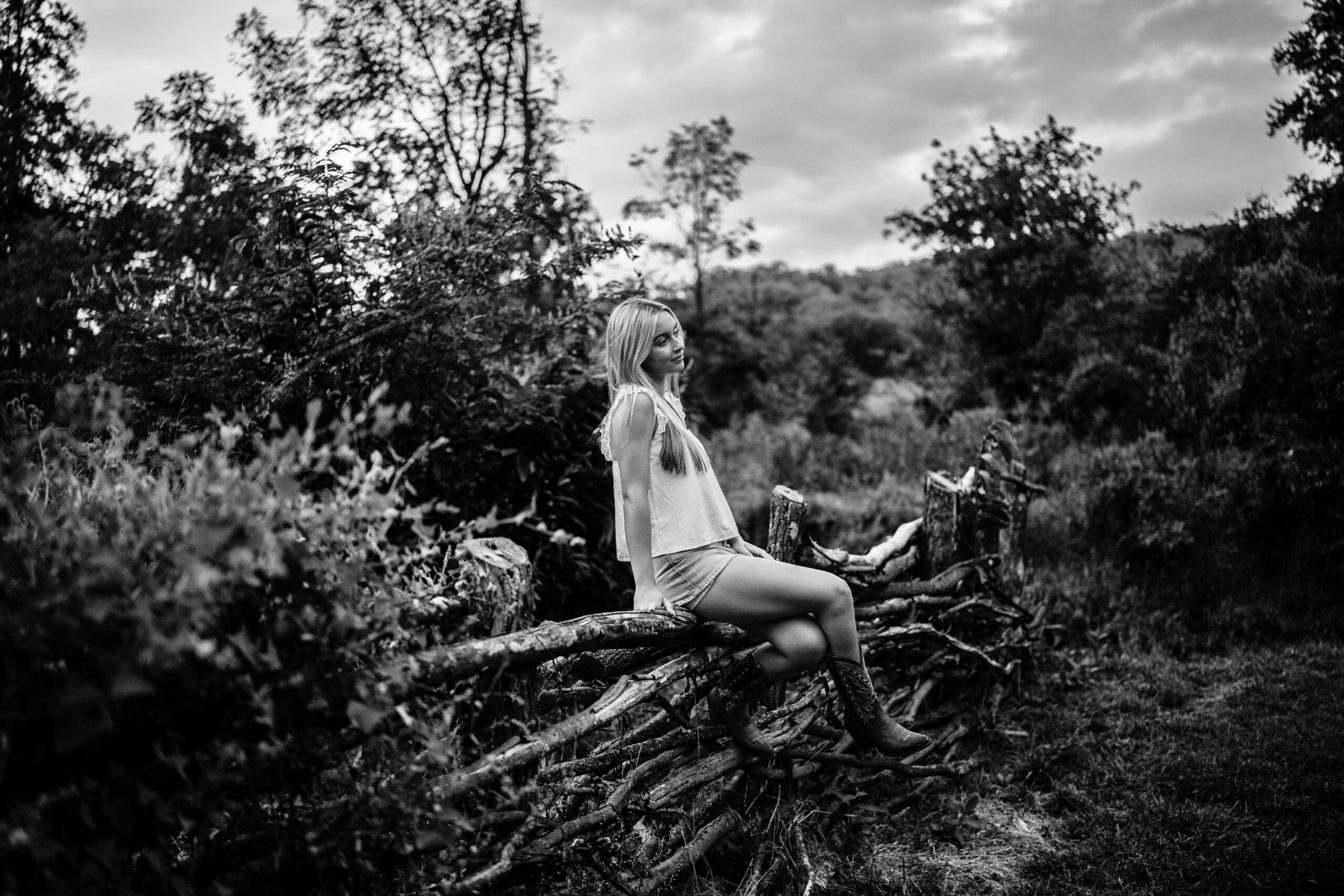 High School senior portraits in wildflower field, sitting on a fence, in black and white