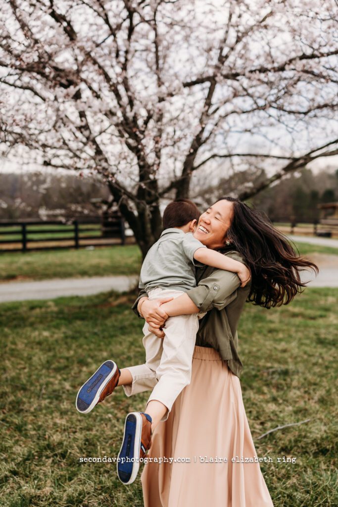 Mother and son dancing under blooming cherry blossom trees in Loudoun County.