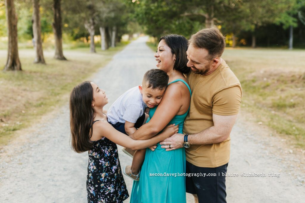 Family of four on tree-lined dirt road.