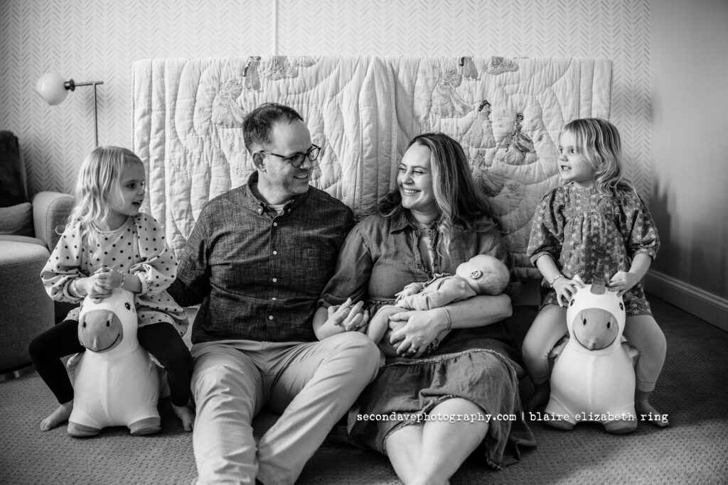 Lifestyle newborn photo with toddler twins in black and white.